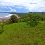 Green meadow with amazing view of tropical beach by the Pacific Ocean.